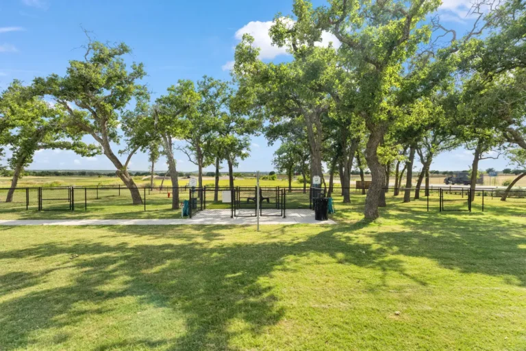 Fenced dog park shaded by live oaks at Lantern Oaks RV Resort