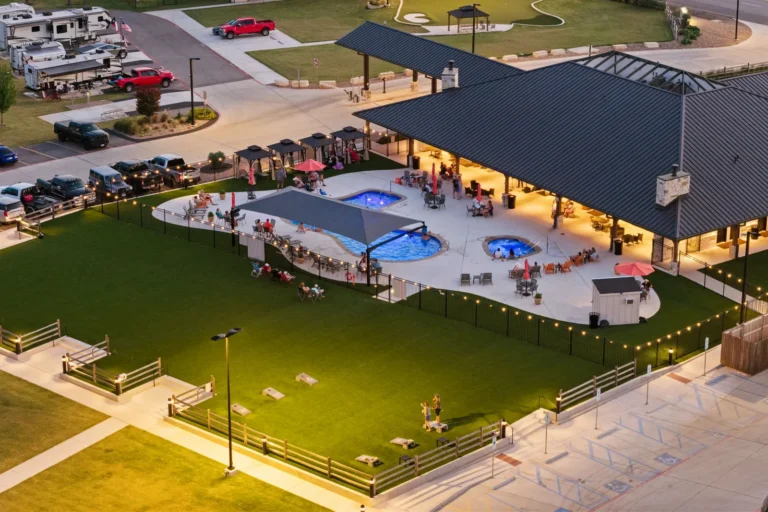 Guests at the lit pool and spa beside the Lantern Oaks clubhouse at dusk