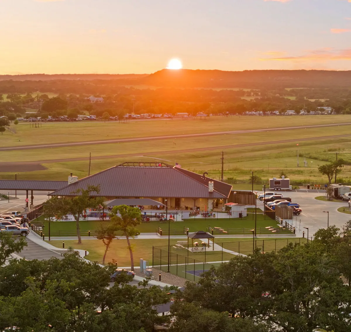 Sun setting over a Hill Country ridge behind the Lantern Oaks clubhouse in Fredericksburg, Texas